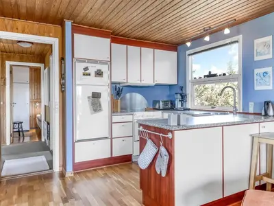 a kitchen with white cabinets and a wooden ceiling at Holiday Home Letje - 500m from the sea by Interhome in Løkken