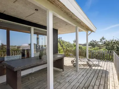 a patio with a table and chairs on a wooden deck at Holiday Home Letje - 500m from the sea by Interhome in Løkken