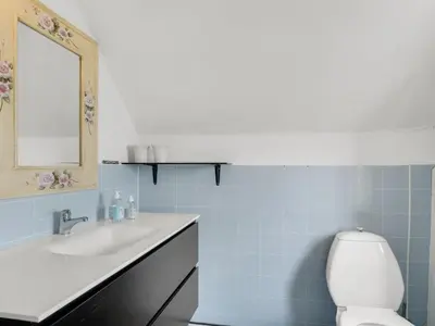 a bathroom with a sink and a toilet and a mirror at Holiday Home Edvardsine - 20m to the fjord by Interhome in Vestervig
