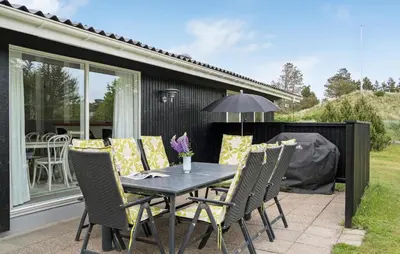 a patio with a table and chairs on a patio at 4 Bedroom Beautiful Home In Blokhus in Blokhus