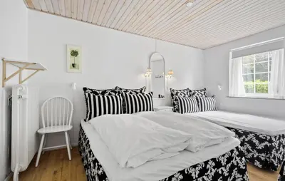 a white bedroom with two beds and a chair at Lejl 4 in Brovst