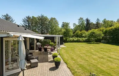 a patio with an umbrella and a lawn at Pet Friendly Home In Farsø With Kitchen in Farsø