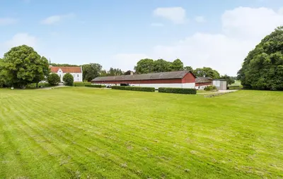 a large field with a barn and a large building at Lejl 3 in Brovst