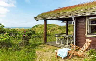 a house with a grass roof and two chairs on a porch at 2 Bedroom Lovely Home In Saltum in Saltum