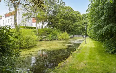 a river with a bridge in the middle of a yard at Hus 2 in Brovst