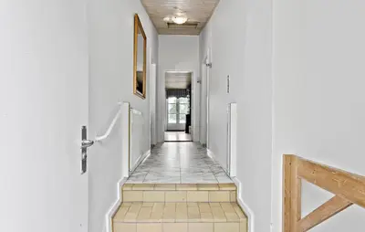a hallway with white walls and a wooden stairway at Hus 2 in Brovst