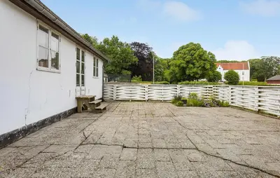 a white building with a bench next to a fence at Lejl 2 in Brovst