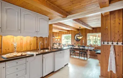 a kitchen with white cabinets and wooden walls at Røgegård Gården in Fjerritslev