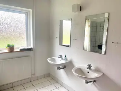 a white bathroom with two sinks and a mirror at Kongshøjgaard in Farsø