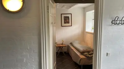 a hallway with a couch in a room with a window at Staudeengen et dejlig sted med fred og ro in Ålestrup