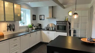a kitchen with white cabinets and a black counter top at Staudeengen et dejlig sted med fred og ro in Ålestrup