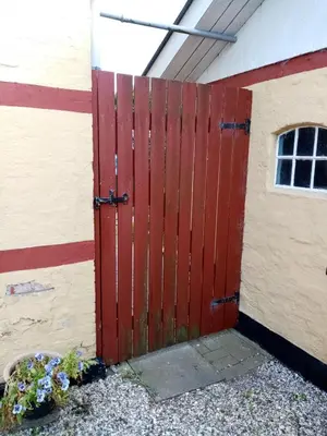 a red door on the side of a building at Hytten in Frøstrup