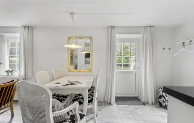a white dining room with a white table and chairs at Lejl 6 in Brovst