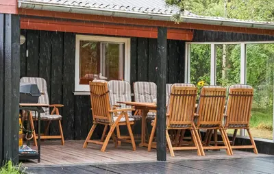 a group of chairs and a wooden table on a deck at Stunning Home In Brovst With Sauna in Brovst