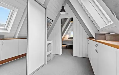 an attic hallway with white cabinets and a bedroom at Nice Home In Farsø With Kitchen in Farsø