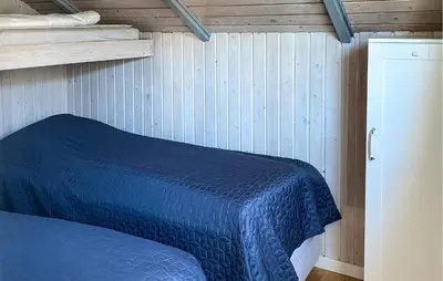 a bedroom with a blue bed and a wooden wall at Cozy Home In Harboøre in Harboør