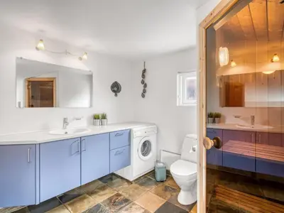 a bathroom with a sink and a washing machine at Holiday Home Hughe - 200m from the sea by Interhome in Frøstrup