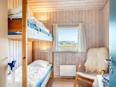 a small bedroom with bunk beds and a window at Holiday Home Hughe - 200m from the sea by Interhome in Frøstrup