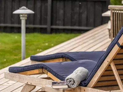 a teddy bear sitting on a rocking chair on a deck at Holiday Home Gedda - from the sea by Interhome in Vestervig
