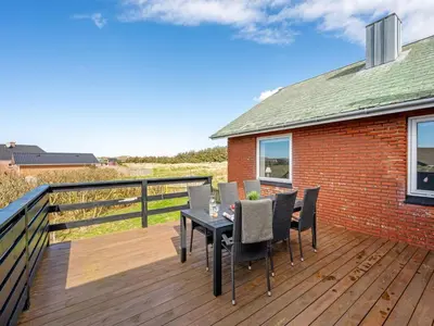 a wooden deck with a table and chairs on it at Holiday Home Hilppa - 400m from the sea by Interhome in Harboør