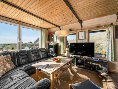 a living room with a black leather couch and a table at Holiday Home Kurt - 75m from the sea by Interhome in Harboør