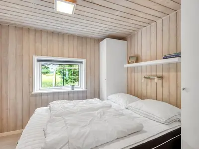 a large white bed in a room with a window at Holiday Home Yngve - 1-2km from the sea by Interhome in Løkken