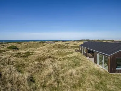 a house on a hill with the ocean in the background at Holiday Home Carit - 450m from the sea by Interhome in Løkken