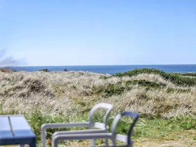 a chair sitting on the beach near the ocean at Holiday Home Carit - 450m from the sea by Interhome in Løkken
