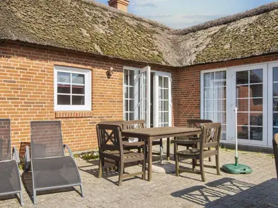 a wooden table and chairs in front of a brick building at 4 star holiday home in Harboøre in Harboør