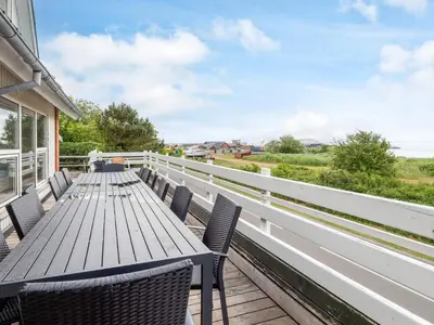 a wooden table and chairs on the balcony of a house at Family Fun with Fjord View - By Traum Ferienwohnungen in Thyholm