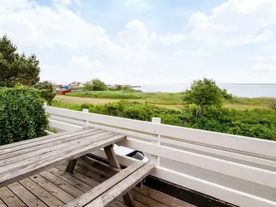 a wooden bench sitting on a porch overlooking the ocean at Family Fun with Fjord View - By Traum Ferienwohnungen in Thyholm