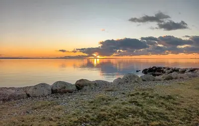 a sunset over a body of water with rocks at 3 Bedroom Awesome Home In Hurup Thy in Sønder Ydby