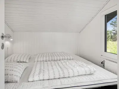 a white bed in a white room with a window at Holiday Home Annlisa - 1km from the sea by Interhome in Blokhus