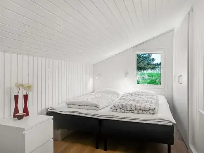 a bed in a white room with a window at Holiday Home Annlisa - 1km from the sea by Interhome in Blokhus