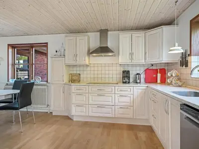 a kitchen with white cabinets and a table and chairs at Holiday Home Satu - 2km from the sea by Interhome in Blokhus