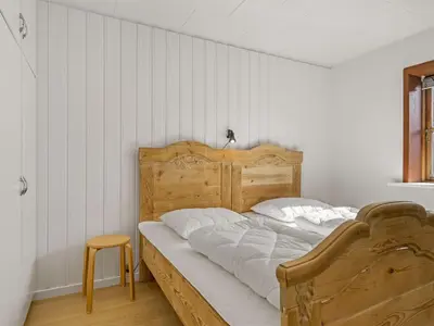 a bedroom with a wooden bed and a wooden stool at Holiday Home Satu - 2km from the sea by Interhome in Blokhus