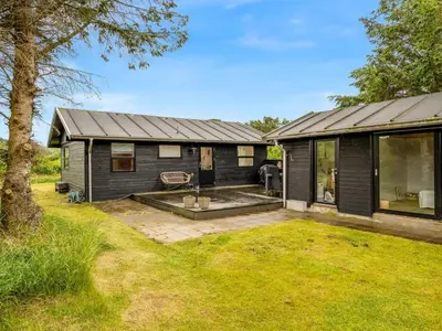 an exterior view of a black house with a yard at Holiday Home Mintha - 400m from the sea by Interhome in Blokhus