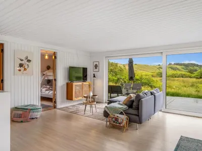 a living room with a couch and a sliding glass door at Holiday Home Mintha - 400m from the sea by Interhome in Blokhus