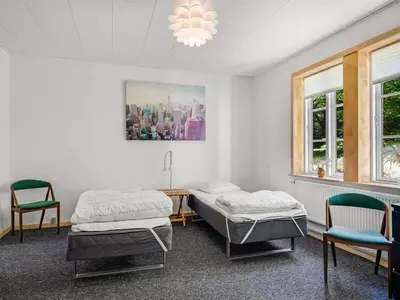 two beds in a room with two chairs and a chandelier at Holiday Home Ejnarine - 600m to the fjord by Interhome in Farsø