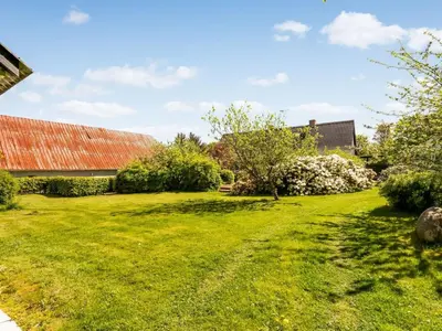 a grassy yard with a red roof and a building at Holiday Home Ejnarine - 600m to the fjord by Interhome in Farsø