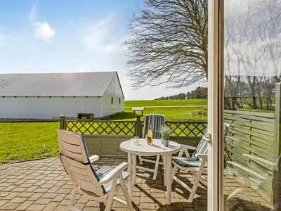 a patio with a table and chairs and a barn at Holiday Home Kerrin - 1km from the sea by Interhome in Hanstholm