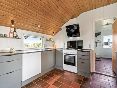 a kitchen with white appliances and a wooden ceiling at Holiday Home Emppu - 250m from the sea by Interhome in Harboør