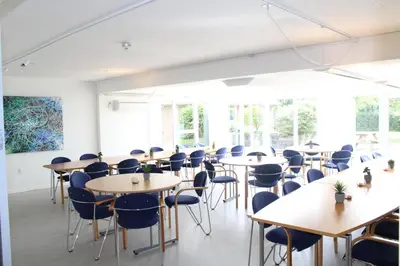 a room with tables and chairs and windows at Hotel Traneparken in Nykøbing Mors