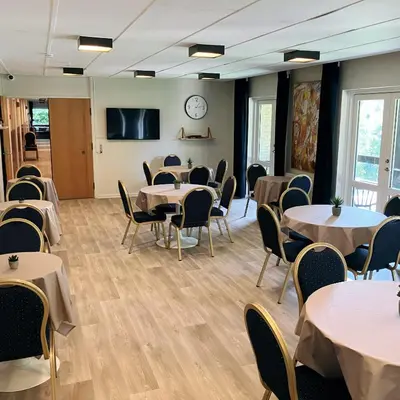 a room with tables and chairs and a clock on the wall at Skovly in Viborg