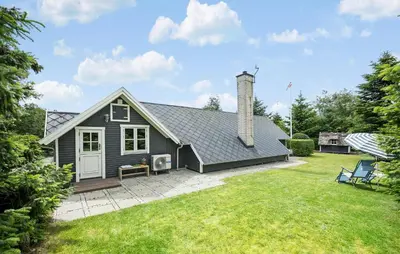 a black house with a lawn in front of it at 2 Bedroom Beautiful Home In Farsø in Farsø
