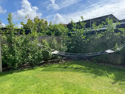 a hammock hanging on a fence in a backyard at Hus tæt ved havn og strand in Thyborøn