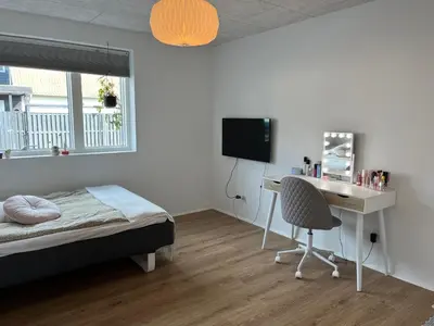 a bedroom with a bed and a desk with a computer at Hus tæt ved havn og strand in Thyborøn