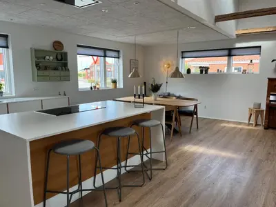 a kitchen with a island with bar stools at Hus tæt ved havn og strand in Thyborøn