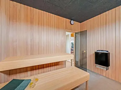a sauna with a bench and a tv at Holiday Home Dreng - 300m from the sea by Interhome in Harboør