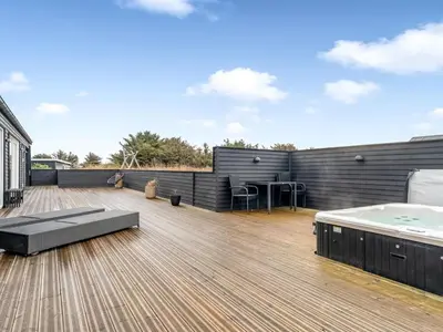 a rooftop deck with a hot tub and a hot tub at Holiday Home Dreng - 300m from the sea by Interhome in Harboør
